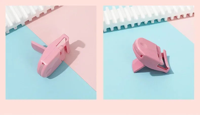 A pink mini folding eyelash curler set resting on a light blue surface next to a white comb.