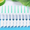 Un juego de hilo dental de silicona blanca con cerdas verdes, dispuestos en fila sobre una superficie azul claro.