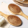 A wooden bamboo comb with numerous bristles is shown on a light background.