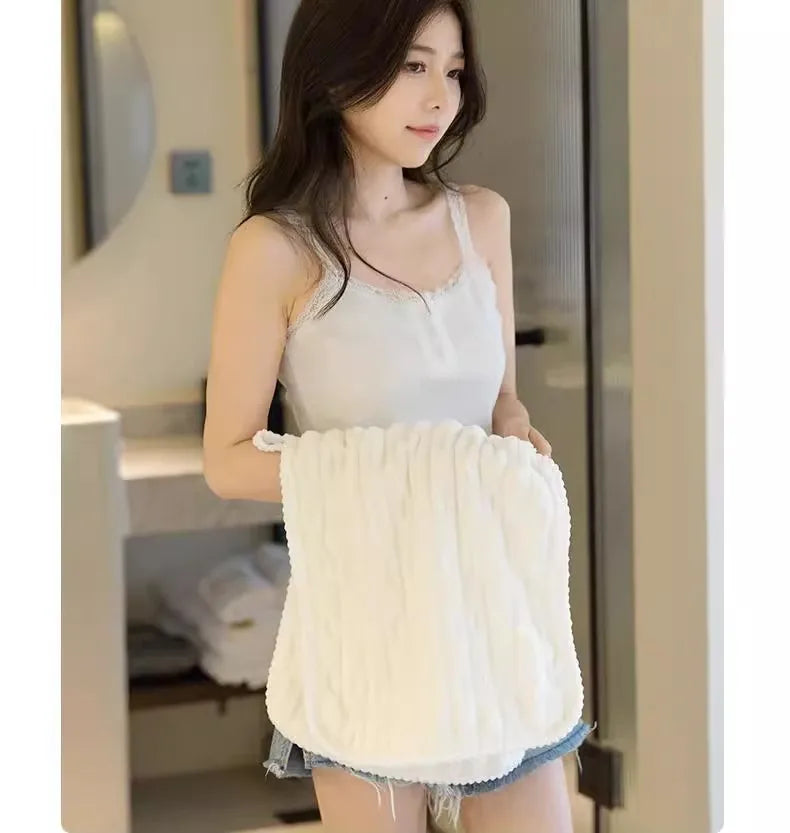 Une femme modélise une serviette de bain en velours de bambou blanc de luxe dans un intérieur lumineux.