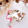 Un ensemble de miroirs de maquillage portables roses et verts avec des poignées en bois posés sur une surface blanche.