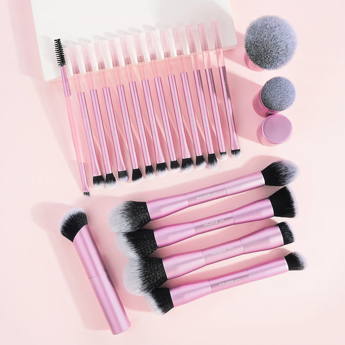 A collection of pink makeup brushes, including foundation and eyeshadow tools, arranged on a light pink background.