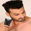 A man is using a black multi-purpose body hair trimmer on his face.