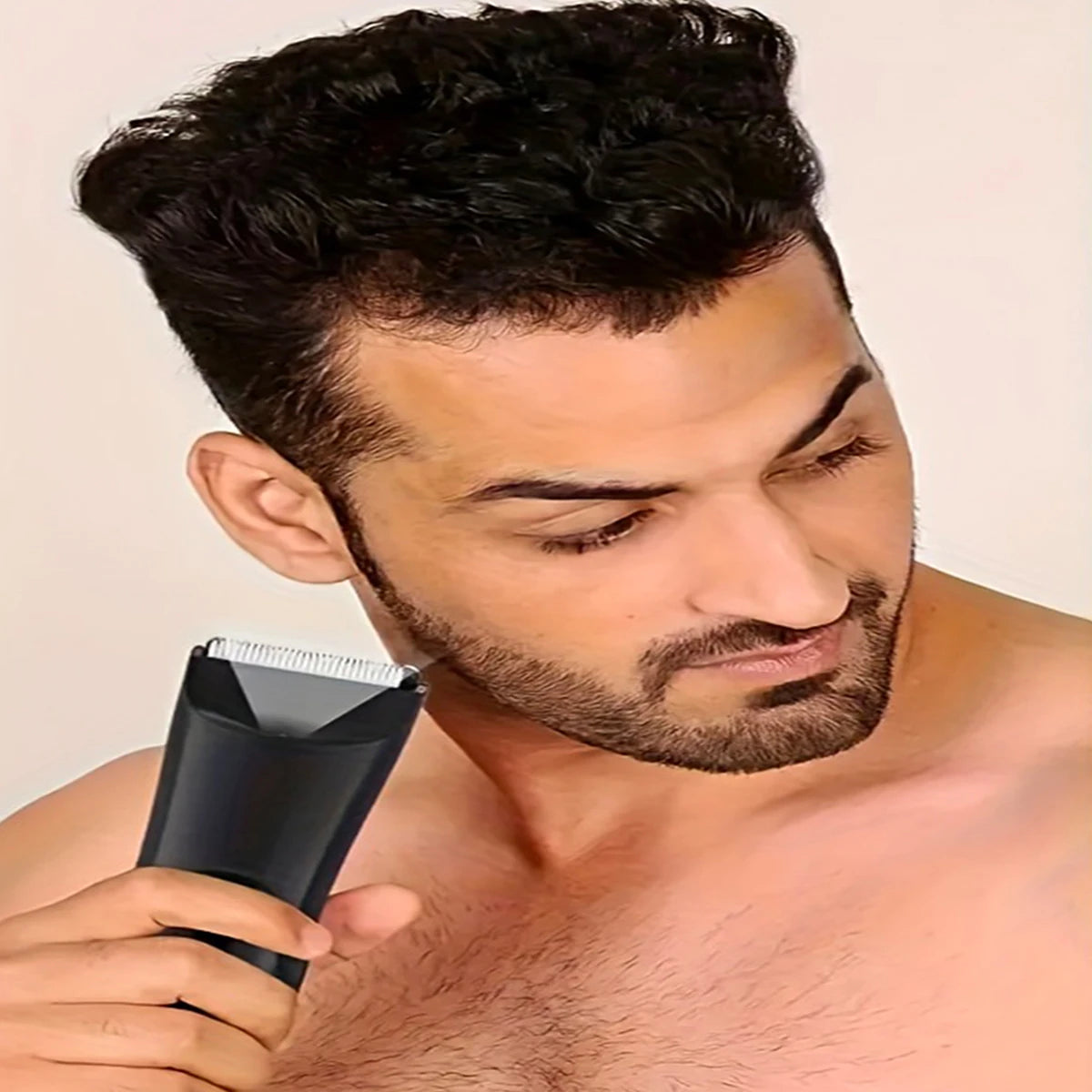 A man is using a black multi-purpose body hair trimmer on his face.