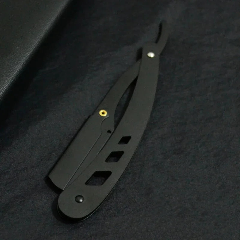 Couteau de rasage pliante antique noir avec poignée et lame, visible sur fond sombre.