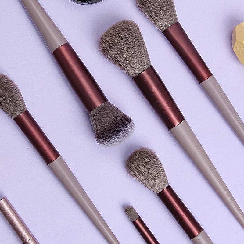 A collection of 13 professional makeup brushes featuring soft synthetic bristles in shades of brown and beige.