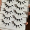 A set of five pairs of dramatic black false eyelashes displayed in a white holder.