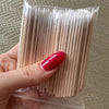 Une main tient un paquet de cotons en bois fins pour retirer le vernis à ongles.