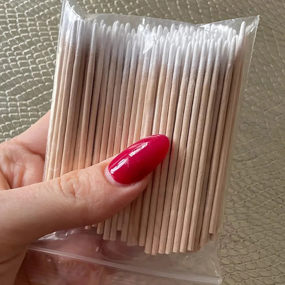 Une main tient un paquet de cotons en bois fins pour retirer le vernis à ongles.