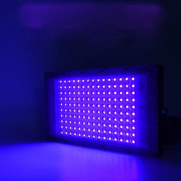 Lampe de polymérisation UV rectangulaire émettant une lumière violette vive, illuminant une surface.