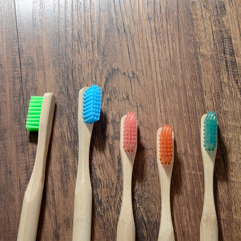 A collection of five bamboo toothbrushes in various colors including green blue pink orange and teal