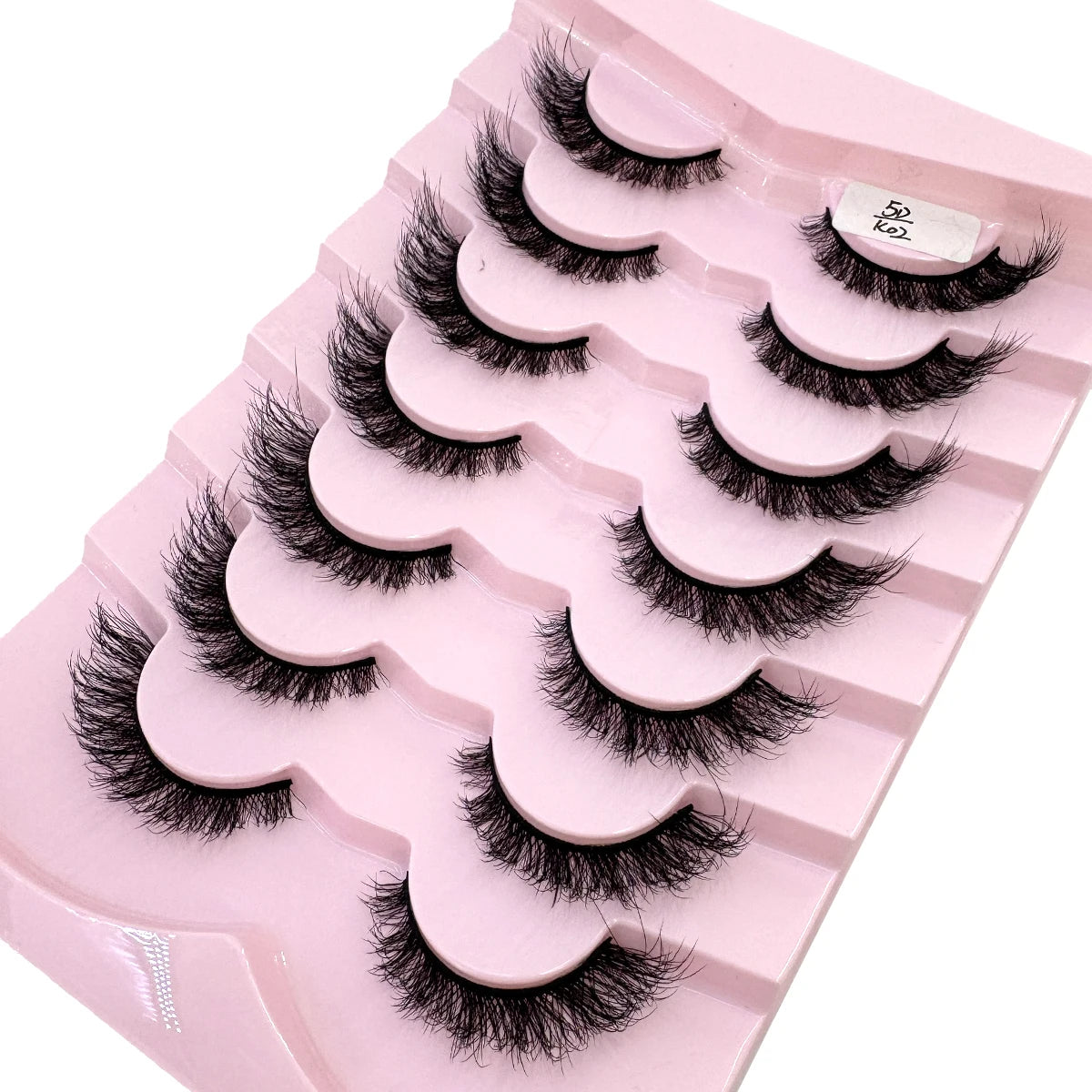 Plateau en plastique rose contenant divers styles de faux cils de renard noirs pour maquillage.