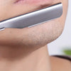 Primer plano de un afeitador manual de acero inoxidable siendo usado en la zona superior del labio.