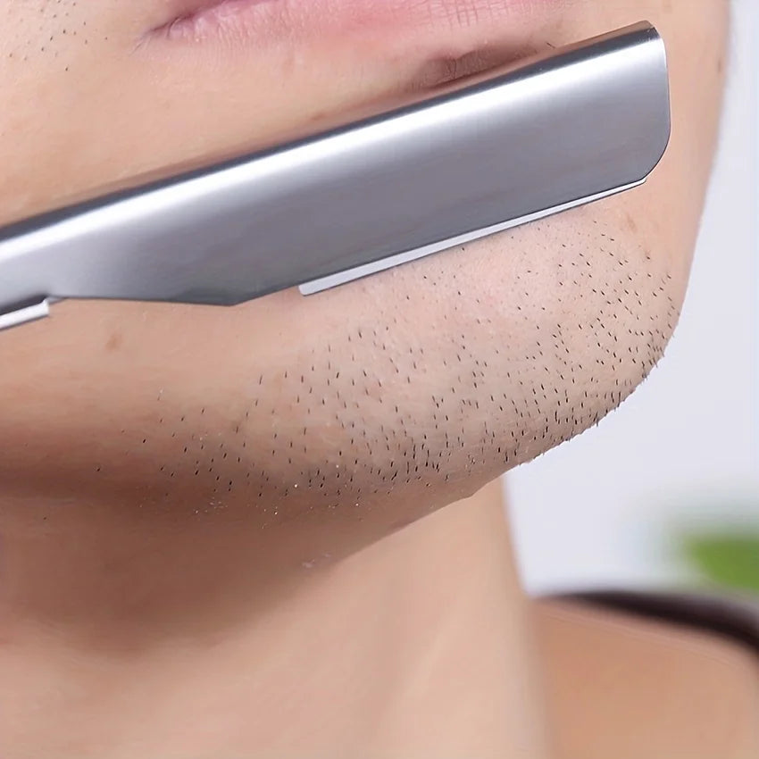 Primer plano de un afeitador manual de acero inoxidable siendo usado en la zona superior del labio.