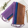 A collection of exfoliating African net body scrub sponges in purple, blue, and brown are displayed on a white surface.