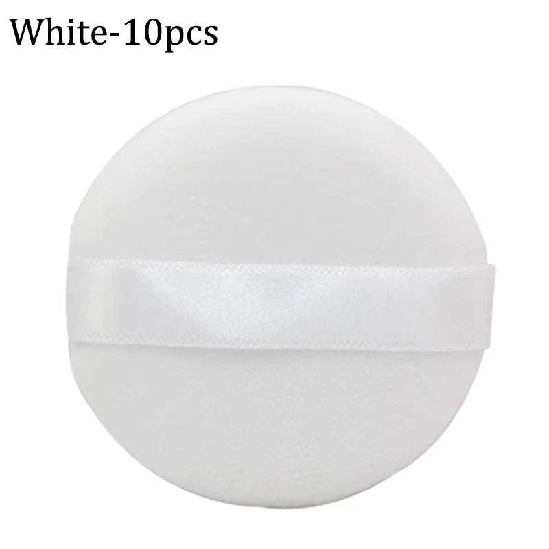 A white makeup puff with a satin ribbon attached for applying concealer or powder.