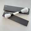 A pair of black and white dual-ended makeup brushes for foundation and contour displayed on a gray surface.