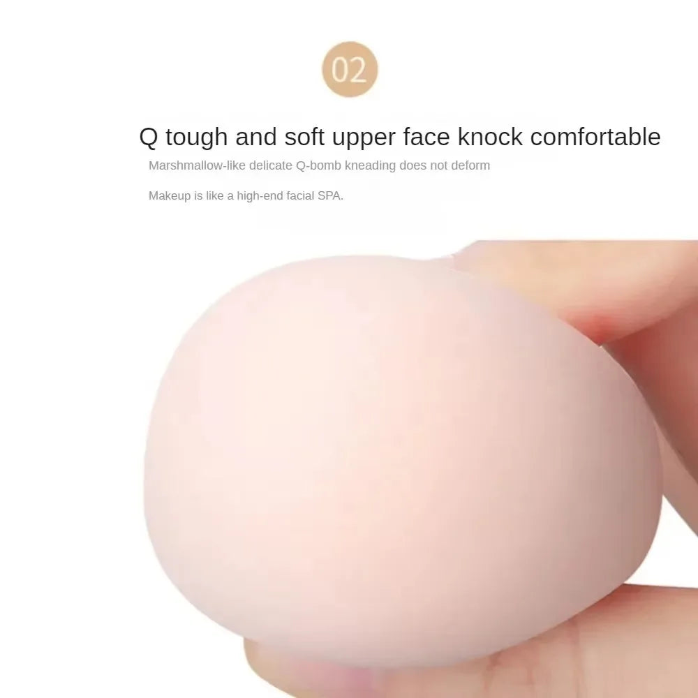 Una mano sostiene una esponja de maquillaje rosa, demostrando su textura suave y firme.