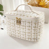 A rectangular knitted canvas makeup pouch in off-white with gold hardware resting on a white surface.