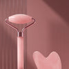 A pink facial massage roller set featuring a heart-shaped scraping plate and a corresponding tool.