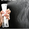 A hand holds a white mist spray bottle, demonstrating a continuous strong spray of ultra fine mist onto a dark surface.
