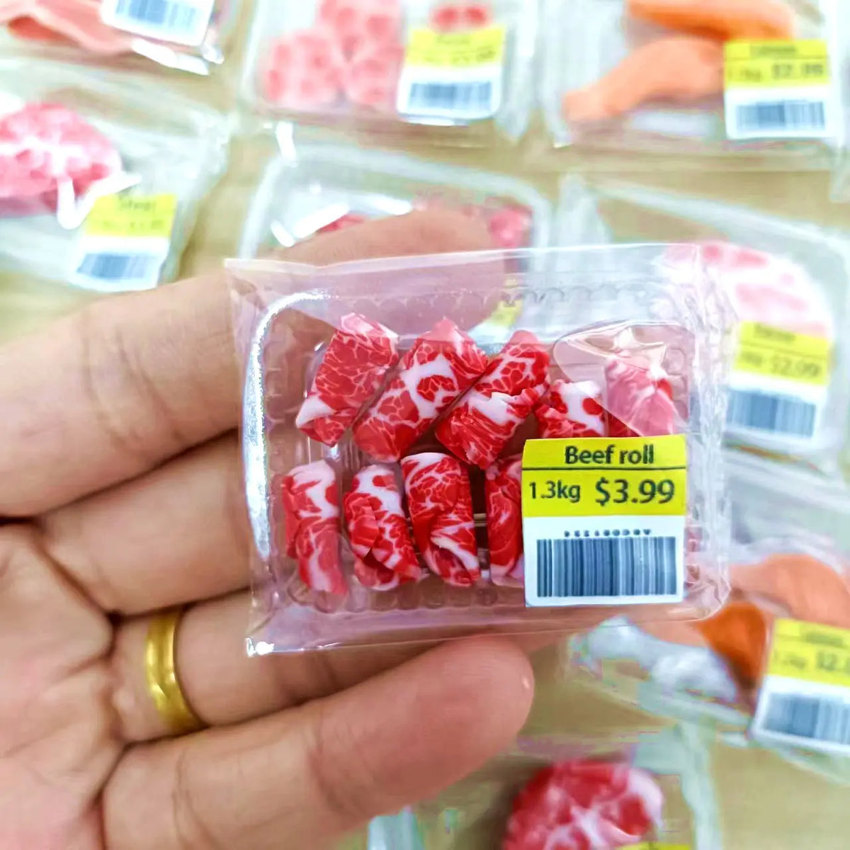 Une main tient un emballage plastique transparent de viande de roulade de bœuf pour un jeu de simulation alimentaire miniatur