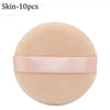 A round, light peach colored makeup puff with a pink ribbon band.