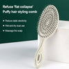 Peigne pour cheveux gonflés de couleur claire sur fond vert foncé.