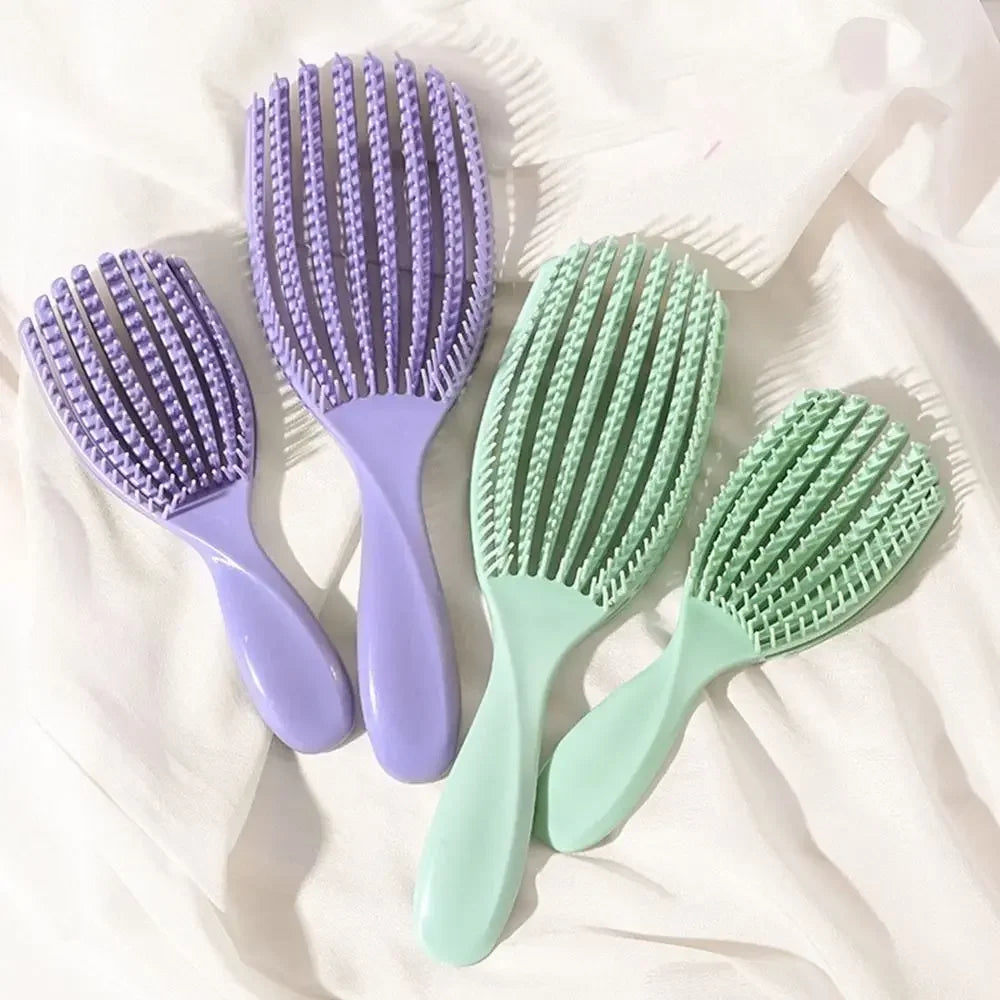 A set of four purple and green massage detangler hair brushes lying on a white surface.