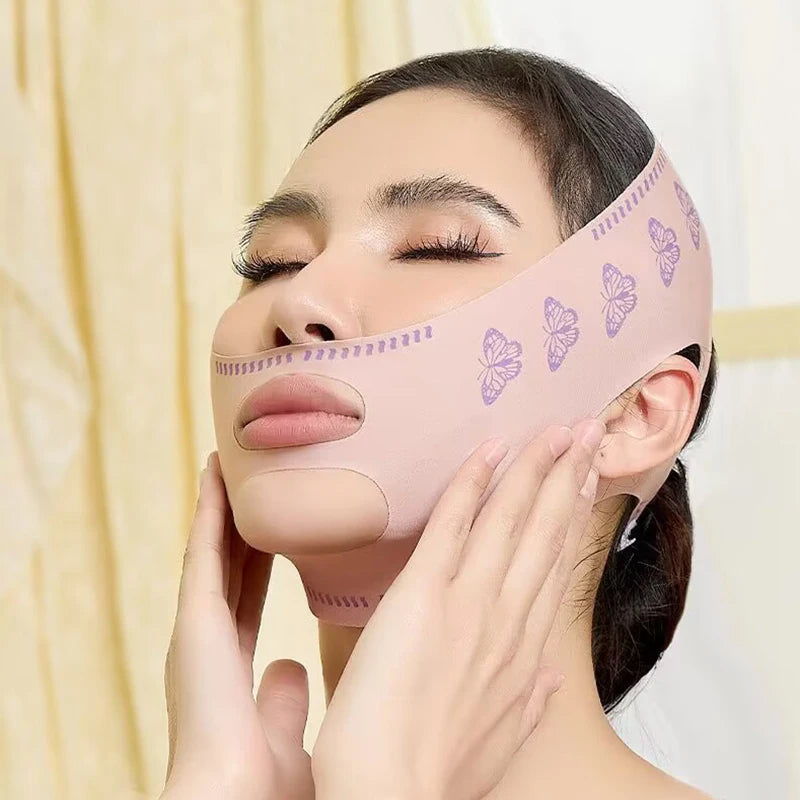 A woman is applying a pink silicone face slimming bandage with butterfly designs to her face.