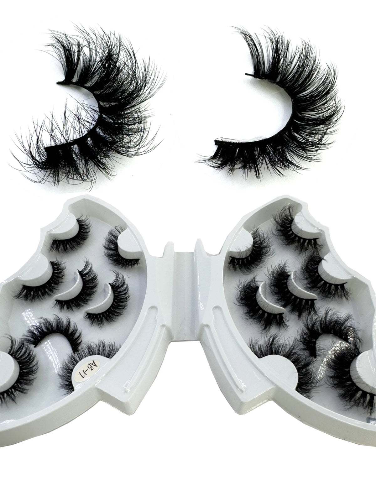 A pair of natural mink striped false eyelash extensions shown as loose lashes and in an open tray.