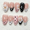 A set of pink and black cat eye false nails featuring white polka dots and 3D floral designs.