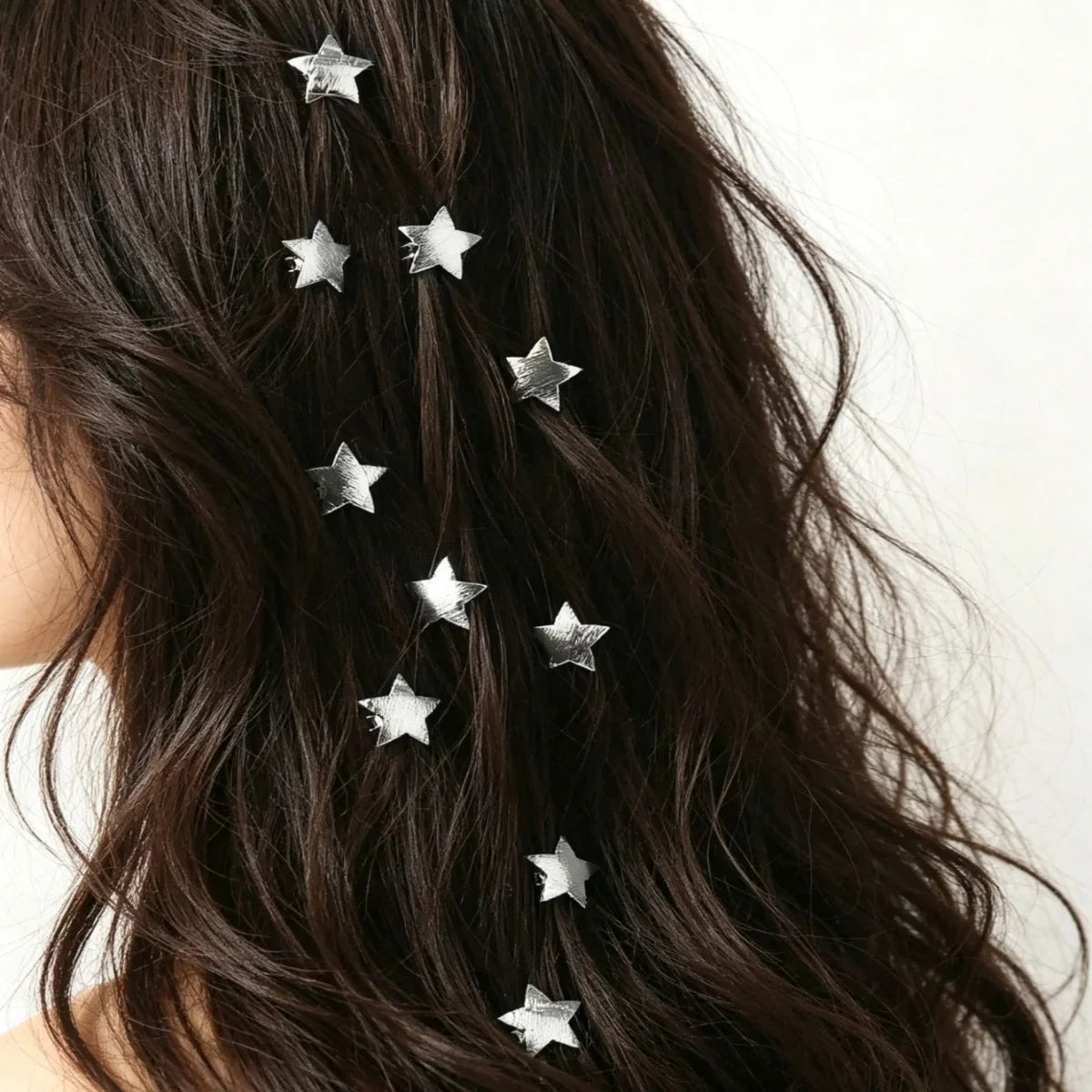 A close-up of dark hair adorned with ten silver star-shaped hairpins.