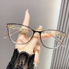 Une main tient une paire de lunettes à monture élégante de type œil de chat avec des accents dorés sur un fond clair.