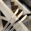 Three clear applicator wands with white bristles used for lip and eyelash extensions.