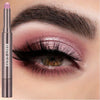 A cosmetic product featuring a long eyeshadow stick in a metallic rose color with a double brush shown next to an eye makeup 