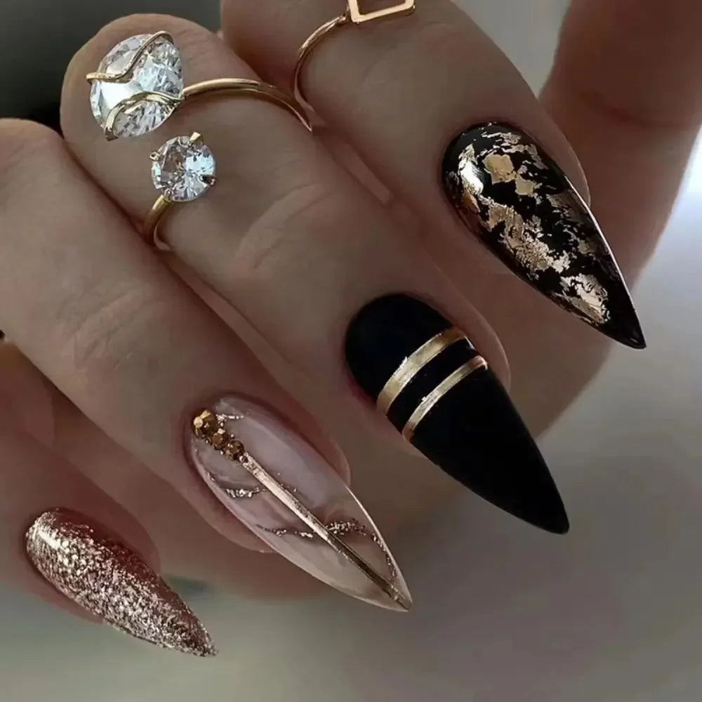 A hand displays press-on false nails featuring a French wavy design in gold and black accents.