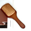 A wooden hair brush with numerous bristles is shown next to a magazine cover.