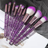 A set of ten professional makeup brushes with purple and pink bristles and metallic handles displayed on a dark background.