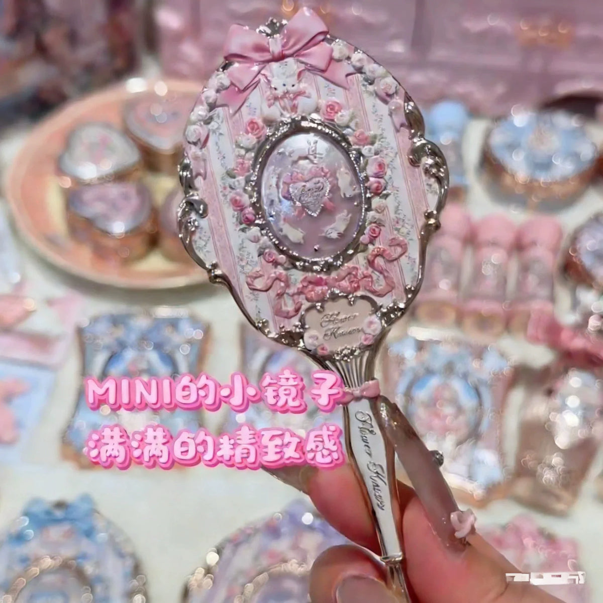 A hand holds a decorative makeup mirror set featuring pink and silver accents on a light background.
