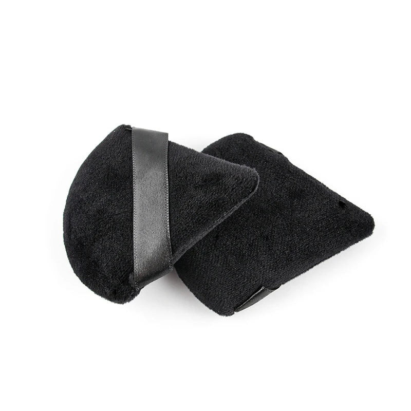 A pair of black velvet powder puffs with black leather straps.