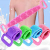 A pink silicone exfoliating brush is shown being used on a person's back, with other colored brushes nearby.