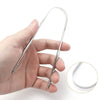 A hand holds a reusable stainless steel tongue scraper and oral brush tool.