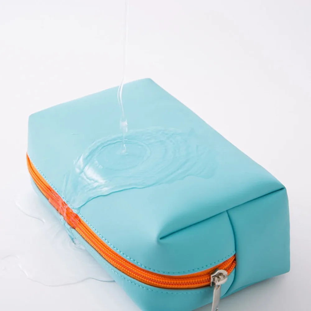 A light blue waterproof PU leather makeup bag with an orange zipper is shown, dripping water.