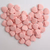 A cluster of pink silicone finger puffs for makeup application arranged in a heart shape.