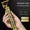A hand holds a gold-colored electric shaver with a metal push shear head, featuring an ornate design.