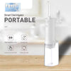 A white portable smart oral irrigator device with a clear water reservoir is shown on a wooden surface.