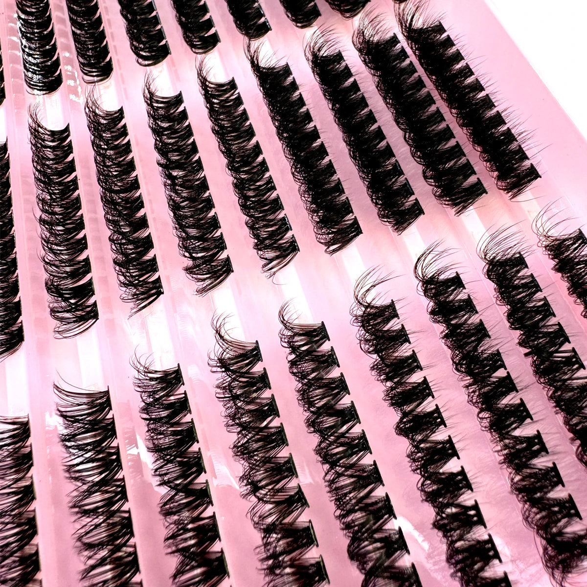 A close-up of black lash clusters applied to pink false lashes for dramatic eye looks.