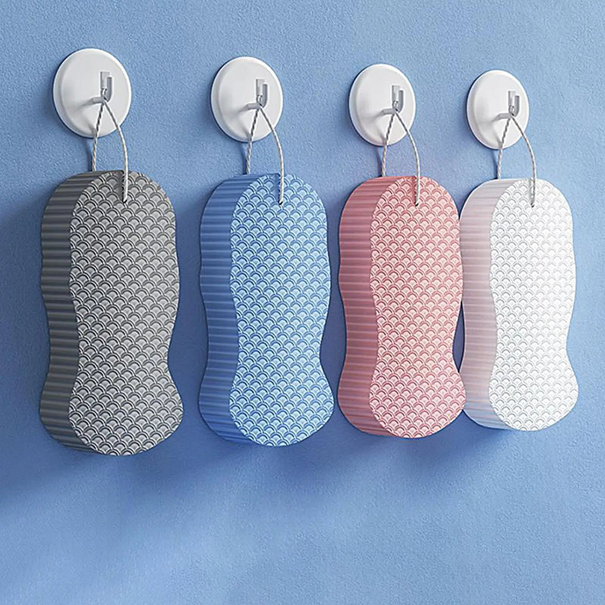 A set of exfoliating bath sponges in various pastel colors, including gray, blue, pink, and white.