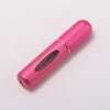 A pink portable refillable perfume bottle with a silver band, shown in a diagonal view.